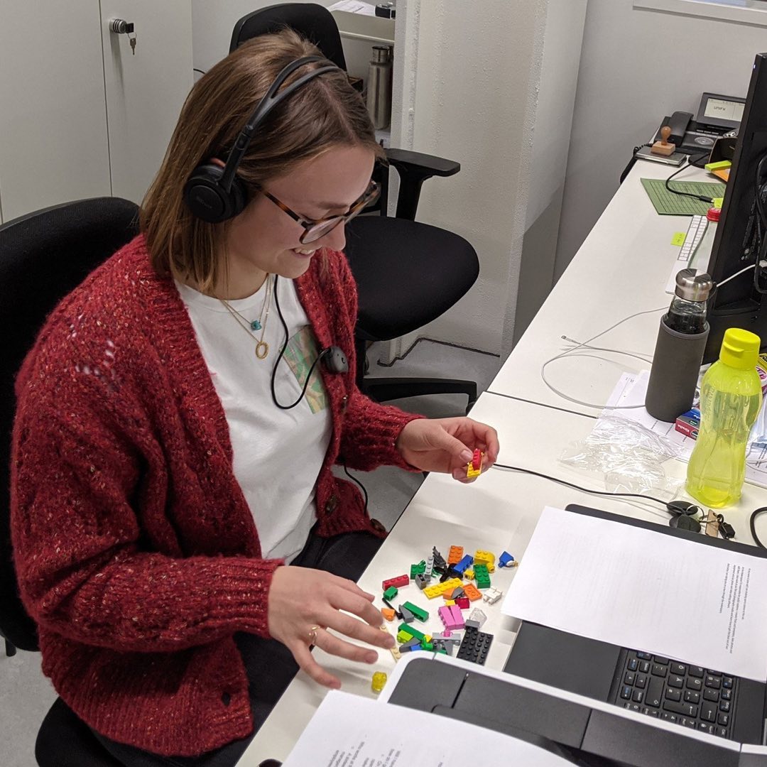 Lena sitzt an einem Schreibtisch und baut Lego zusammen.